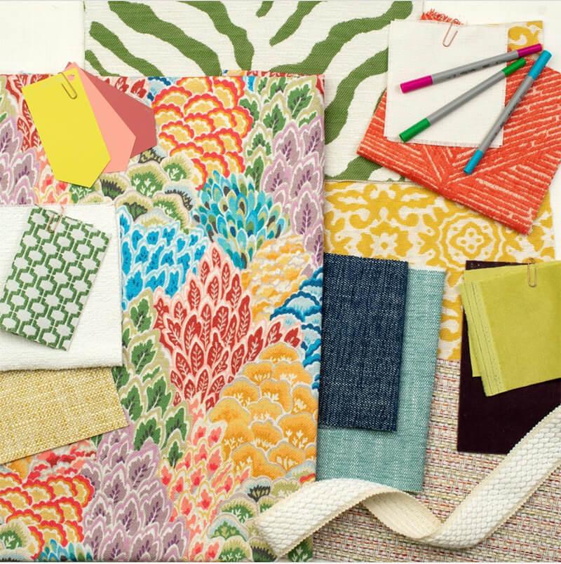 Colorful fabric swatches in a variety of patterns and sizes laid out on a table
